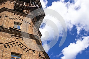 Old water tower made of ancient bricks on a background of blue sky with clouds