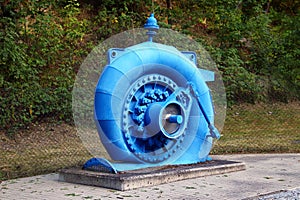 Old water turbine generator in blue spiral casing