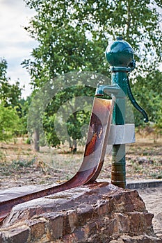 Old waterpump made of steel with a rusty channel attached where the water is catched photo