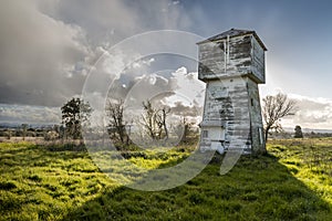 An old weather beaten vineyard water tower stands in a field