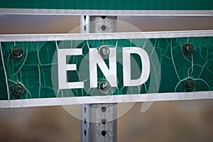 Old weather and sun stressed street sign states it is the END