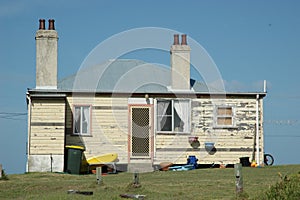 An old weatherboard house, against a blue sky.