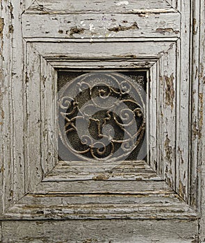 Old weathered antique wooden door panel frame with metal decorative inset. Paint is peeling. Rough solid wood is square.