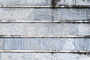 Old weathered blue gray stone wall with lichen with horizontal lines, as a textured background