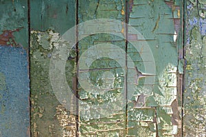 Old weathered boards, with peeling green and blue paint faded in the sun, cracks and colored spots.