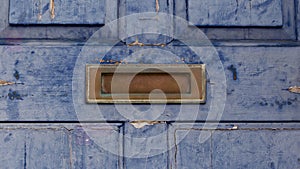 Old weathered brass letterbox on old blue grunge front door
