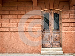 Old weathered brown door made of wood, orange wall in Croatia