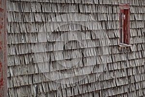 Old weathered cedar shakes shingles barn with red window