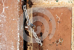 Weathered door of an abandoned house locked with chain and a rusty padlock