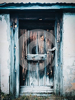 Old, weathered door in a dilapidated building with worn, peeling paint and signs of damage