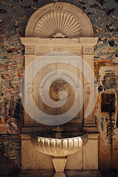 Old weathered drinking fountain with a sculpture of lion`s head