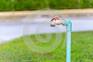 Old and weathered garden`s faucet water tap in beautiful sunlight with green grass in background