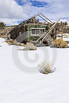 Old weathered Ghost Town buildings in the desert during winter with snow.