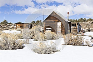 Old weathered Ghost Town buildings in the desert during winter with snow.