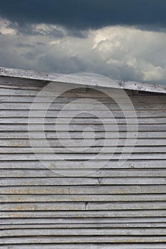 Old weathered grey damaged wooden farm shack wall texture, large detailed textured rustic grungy vertical background, moody sky