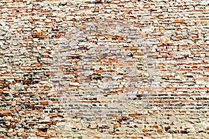 Old and weathered grungy red brick wall partly covered by excess cement and grey paint