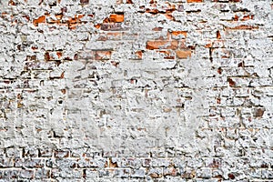 Old and weathered grungy red brick wall partly painted with white peeling paint and covered by old cement as texture background