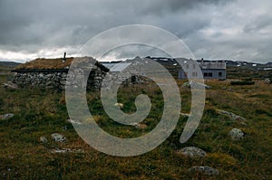 old weathered houses on field with tall grass and stones, Norway, Hardangervidda