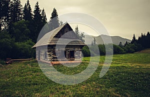 Old and weathered hut - chamkova stodol under the Kralova Hola mountain in rainy day. Old cabin in the green forest meadow with