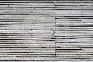 Old weathered natural grey damaged wooden farm shack wall, rustic grungy horizontal background closeup, broken boarding pattern