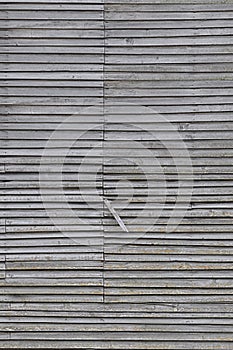 Old weathered natural grey damaged wooden farm shack wall, rustic grungy vertical background closeup, broken boarding pattern