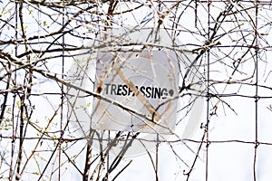 Old and weathered No trespassing sign posted to wire fence, safe