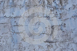 Old weathered painted wall background texture. White dirty peeled plaster wall with falling off flakes of paint