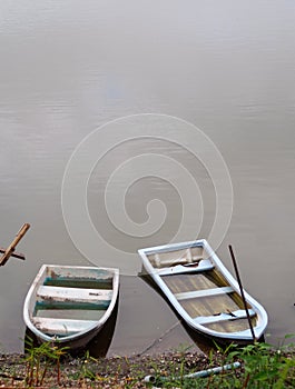 Old weathered plastic fade out color boats on smooth water surface