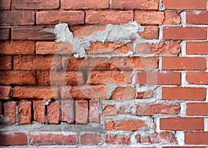 Old weathered red brick wall with obvious signs of disrepair