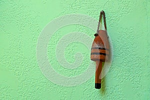 Old weathered red buoy on green wall