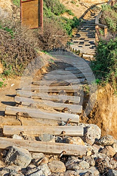 Old weathered stair case made from wooden logs leading to the beach