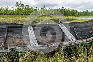 Old and weathered wooden boat wreck laying on the ground in beautiful norwegian landscape