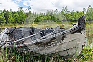 Old and weathered wooden boat wreck laying on the ground in beautiful norwegian landscape