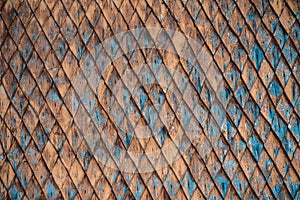 Old weathered wooden wall with ornament painted in brown and blue.