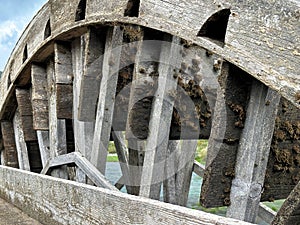 Old weathered wooden watermill wheel on the slow river water