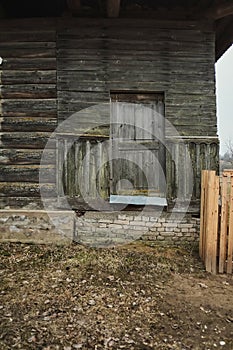 Old weathered wooden window with hinges on the old wooden dilapidated house