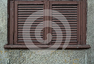 Old, weathered wooden window shutters with peeling paint. Close up.