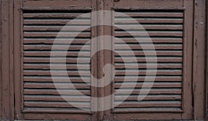 Old, weathered wooden window shutters with peeling paint. Close up.