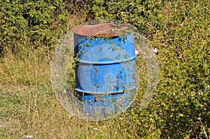 Old weathered and worn blue oil barrel in nature