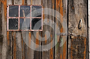 Old weathered and worn wooden planks with door and pink framed window