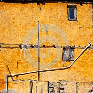 Old weathered yellow facade of a house with vintage windows