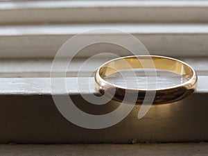 An old wedding ring in gold, on a white shelf