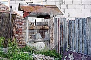 Old well with a bucket on a chain near a brick wall