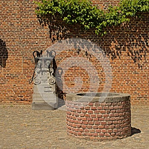 Old well and water pump decorated with sculpted faces and decorations