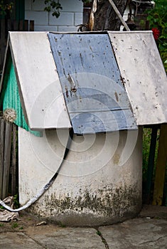Old well with a wooden door and an aluminum bucket