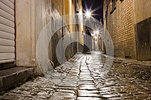 Old wet cobblestone street after rain at night