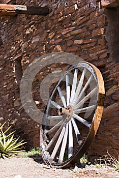 Old wheel near a stone wall