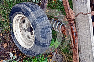 An old wheel with a rusty spring on a cart in the yard