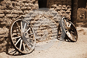 Old wheel from vintage cart beside wall