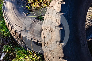 Old wheels of unrecycled cars thrown in a natural field pollute the earth